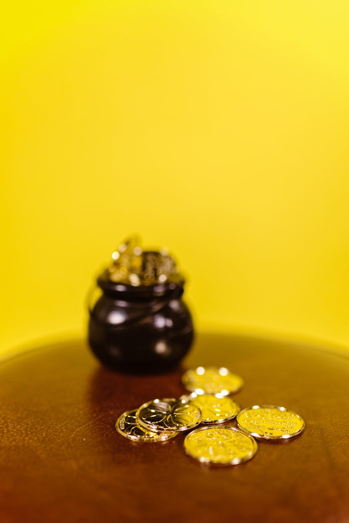 A small black pot filled with golden coins on a yellow backdrop, exuding wealth and fortune.